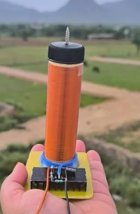 Homemade Tesla coil with copper winding, held in hand outdoors